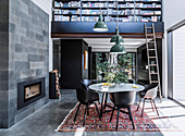 Runder Tisch mit Schalenstühlen vor Terrassentür, Bücherregal mit Leiter in hohem Wohnraum