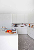 White fitted kitchen with island counter and stone worksurfaces