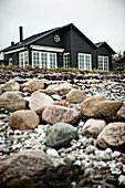 View from shingle beach to black wooden house with lattice windows