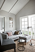 Wohnzimmer in Grautönen in einem Holzhaus mit offener Decke