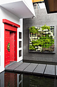 Eingangsbereich mit roter, chinesischer Tür und vertikaler Bepflanzung