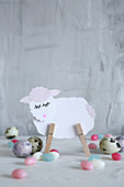 Lamb made from paper and clothes pegs amongst Easter eggs