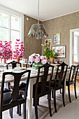 Set table and old chairs in dining room with vintage-style wallpaper