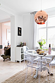 Runder Esstisch mit Designerstühlen vor Fenster in offener Küche