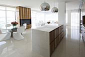 Marble kitchen counter, white designer chairs around glass table and TV cabinet in open-plan interior