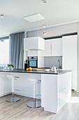 Moderne offene Küche in Weiß mit Küchentheke und Barhockern