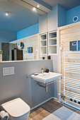 Badezimmer mit Spiegelwand über weißem Waschbecken