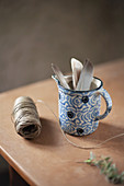 Feathers in blue-and-white jug and reel of twine on table