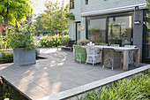 Wooden table and designer chairs on terrace with concrete flags