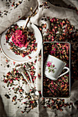 Tasse mit Blumenmotiv in einer Blechdose mit Rosentee
