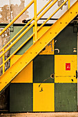 Gelbe Stahltreppe über grün-gelber Schiebetür in einer Fabrik