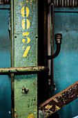 Yellow numbers on steel girder with peeling paint