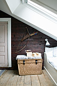 Wicker basket next to bed below sloping ceiling with skylight