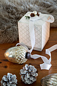 Gift box, Christmas-tree bauble and pine cones on wooden table