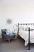 Gray upholstered armchair and bedside table next to bed in bedroom