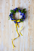 Small wreath of grape hyacinth flowers with yellow ribbon on wooden surface