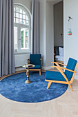 Blue armchairs and side table on round rug next to window