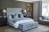 Double bed with upholstered headboard and matching storage bench in bedroom with dark accent wall