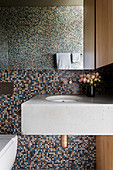 Beton-Waschtisch vor Mosaikfliesen im Bad