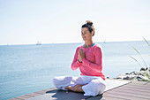 Frau in Meditationssitz am Meer