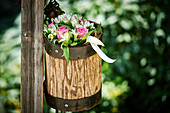 Bouquet in wooden pot on wooden pole in garden