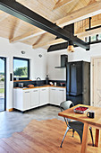 Kitchen and dining table in open-plan interior of converted barn