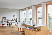 Küchentheke mit Barhocker vor Fensterfront in hellem, offenem Wohnraum