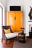 Armchairs and side table in front of yellow Asian cupboard