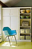 Blue shell chair on yellow floor in front of kitchen cupboards