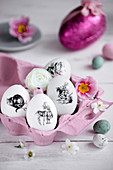 Ostereier mit schwarz-weißen Aufklebern in rosa Eierschachtel