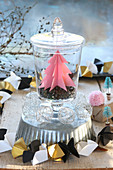 Pink paper Christmas tree in jar on top of cake tin with origami garland