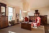 A pair of antique red corduroy wing chairs in sitting room with regency chest of drawers and a model Italian palazzo