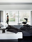 Designer furniture in minimalist, monochrome bedroom; person walking past windows