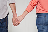 Frau und Mann gehen Hand in Hand (Körpersprache: 'Schüchternheit')