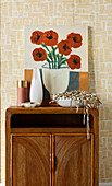 Picture with floral motif and bowl with tinsel on retro cupboard