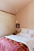 Ländlich rustikales Schlafzimmer mit Natursteinwand und Bett mit Vintage-Quilt