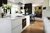 View into living space from modern kitchen with white cabinets