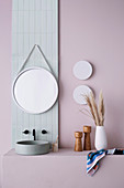 Vanity with countertop basin and round mirror on pastel wall