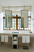 Cantilever limestone vanity area with pivoting mirrors