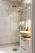 Marble countertop sink, glass shower screen and brass shower fittings in elegant bathroom