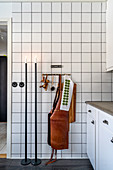 Candlesticks and leather apron in kitchen with white-tiled wall