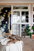 Wall made from windows separating hallway with rose-patterned wallpaper