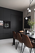 Braune Lederstühle am Esstisch in der Küche mit schwarzen Fronten