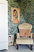 Oriental picture above old-fashioned armchair against vintage-style wallpaper