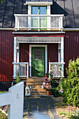 Falu-red Swedish house with green front door and veranda