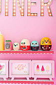 Retro figurines and picture frames on shelves on pink wall