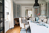 Stylish seating, tiled stove and patterned wallpaper in dining room