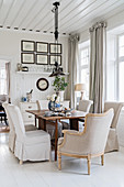 Loose-covered chairs and armchair in dining area with white wooden floor