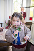 Mädchen im Strickpulli riecht am Blumensträußchen