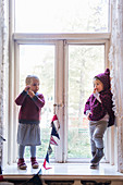 Zwei Mädchen in nachhaltiger Mode am Altbaufenster